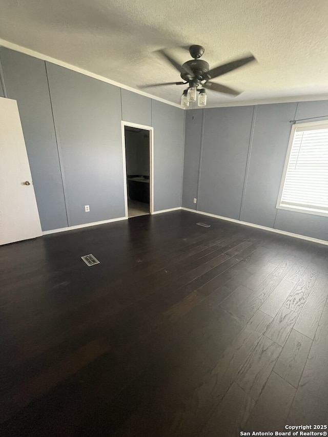 207 S Edwards, Charlotte, TX 78011 - empty room with ceiling fan, dark wood-style floors, a textured ceiling, and a decorative wall
