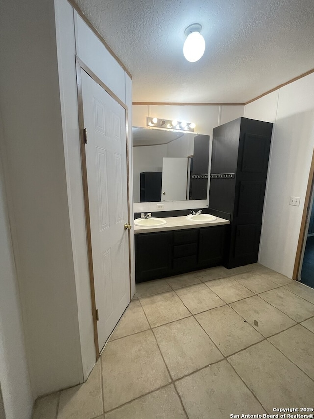 207 S Edwards, Charlotte, TX 78011 - bathroom featuring double vanity, a textured ceiling, and tile patterned floors