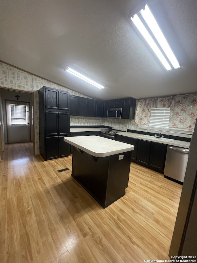 207 S Edwards, Charlotte, TX 78011 - kitchen featuring appliances with stainless steel finishes, wallpapered walls, light countertops, dark cabinets, and a center island
