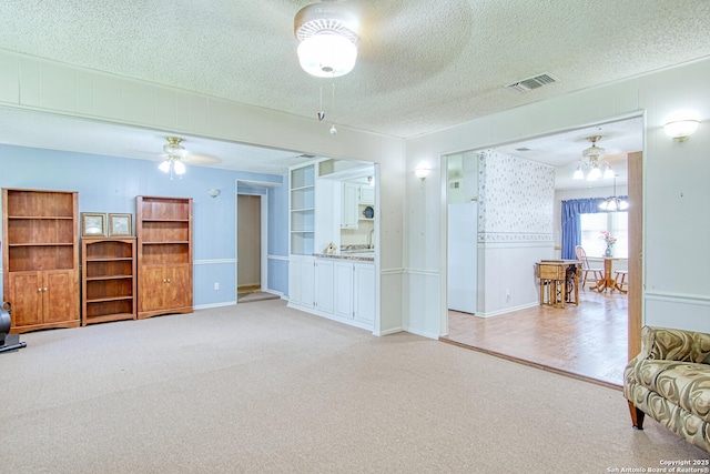 323 Hatcher Ave, San Antonio, TX 78223 - living room with light carpet, a textured ceiling, a ceiling fan, and a chandelier