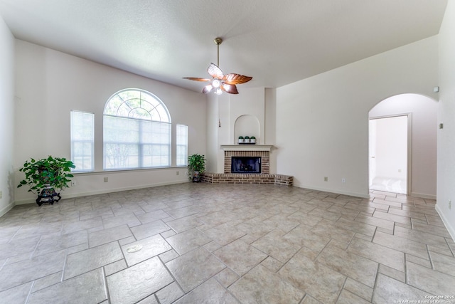 15311 Tamaron Pass, San Antonio, TX 78253 - unfurnished living room with ceiling fan, arched walkways, a fireplace, and light stone finish floors
