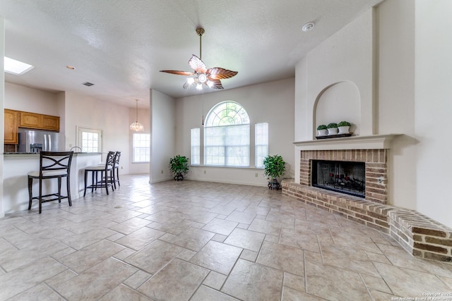 15311 Tamaron Pass, San Antonio, TX 78253 - living area with a fireplace, ceiling fan, light stone finish floors, a textured ceiling, and a chandelier
