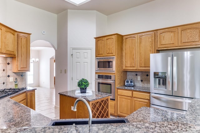 15311 Tamaron Pass, San Antonio, TX 78253 - kitchen featuring appliances with stainless steel finishes, backsplash, arched walkways, stone counters, and light tile patterned flooring