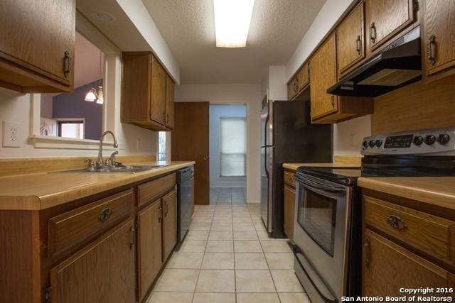 9218 Woodheather, San Antonio, TX 78254 - kitchen with stainless steel range with electric stovetop, under cabinet range hood, dishwasher, light tile patterned flooring, and brown cabinets