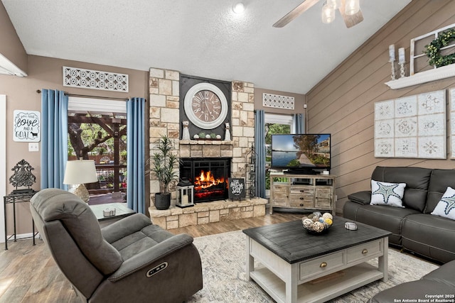 2026 Encino Vista St, San Antonio, TX 78259 - living area featuring wood finished floors, vaulted ceiling, ceiling fan, a stone fireplace, and a textured ceiling