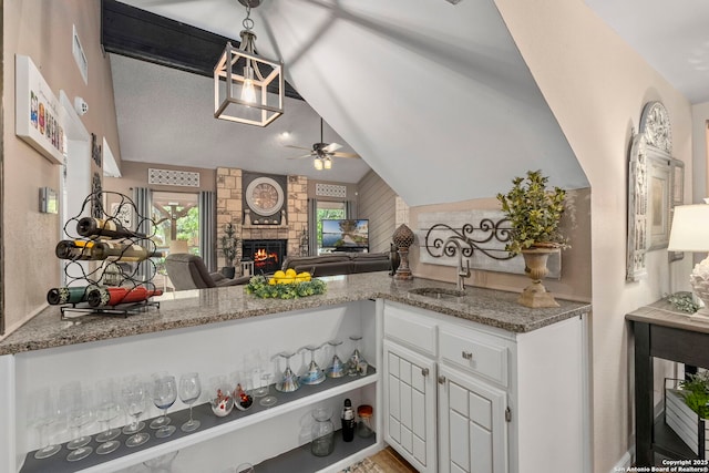 2026 Encino Vista St, San Antonio, TX 78259 - kitchen featuring ceiling fan, a fireplace, vaulted ceiling, white cabinets, and light stone countertops