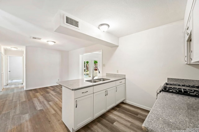 162 Morning Vly, San Antonio, TX 78227 - kitchen featuring a peninsula, wood finished floors, white cabinetry, and gas stove