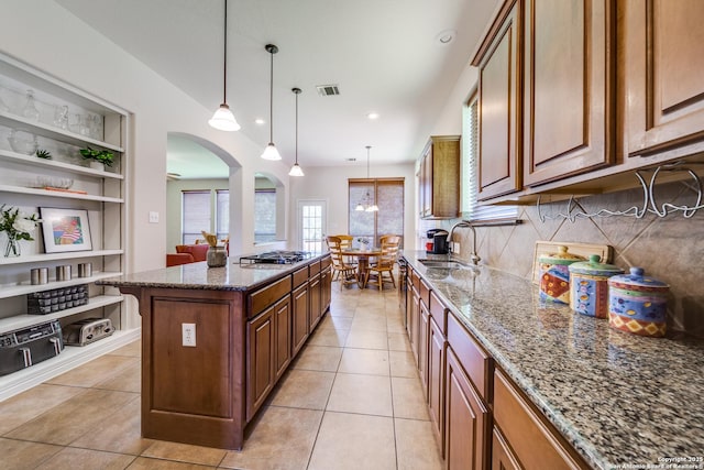 139 Sable Hts, San Antonio, TX 78258 - kitchen featuring a kitchen island, gas stovetop, arched walkways, dark stone counters, and light tile patterned floors