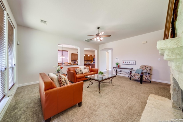 139 Sable Hts, San Antonio, TX 78258 - living room with arched walkways, light colored carpet, ceiling fan, and a stone fireplace