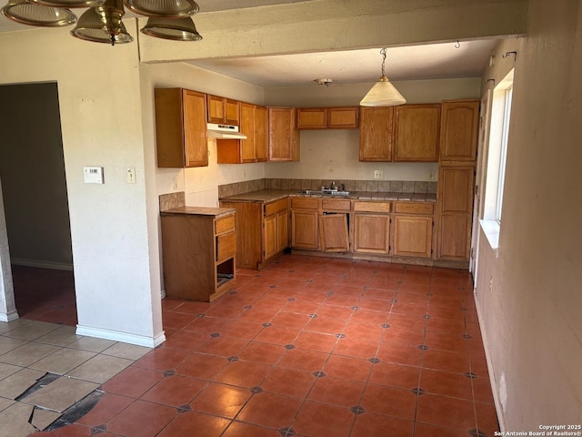 394 Dorie, San Antonio, TX 78220 - kitchen with under cabinet range hood, brown cabinets, tile patterned floors, and pendant lighting