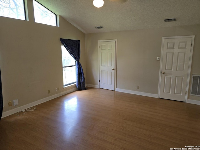 14107 Moss Farm, San Antonio, TX 78231 - empty room with a textured ceiling, healthy amount of natural light, wood finished floors, and lofted ceiling