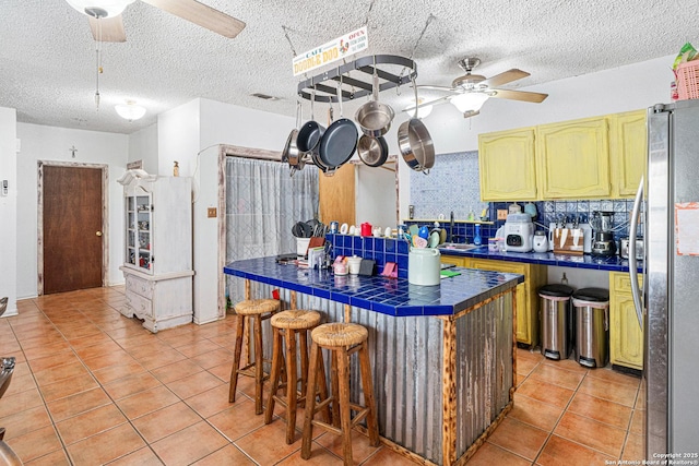 114 Pace Miller, Del Rio, TX 78840 - kitchen with ceiling fan, tile countertops, freestanding refrigerator, light tile patterned flooring, and a textured ceiling
