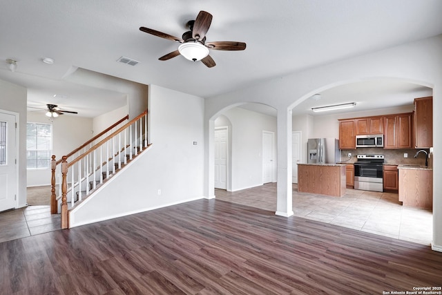 2702 Harvest Crk, San Antonio, TX 78244 - unfurnished living room featuring a ceiling fan, light wood-type flooring, stairway, and arched walkways