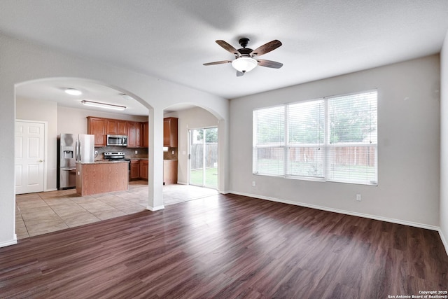2702 Harvest Crk, San Antonio, TX 78244 - unfurnished living room with light wood-style floors, ceiling fan, and arched walkways