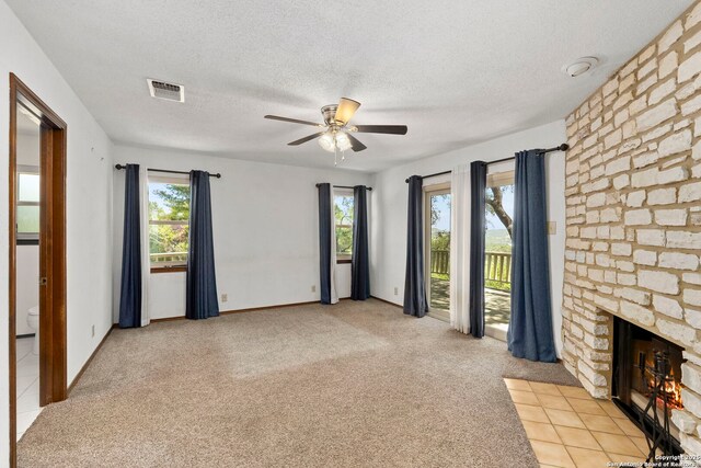 25615 Dull Knife Trl, San Antonio, TX 78255 - unfurnished living room featuring ceiling fan, a textured ceiling, a stone fireplace, and light carpet