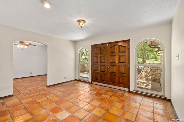 25615 Dull Knife Trl, San Antonio, TX 78255 - foyer entrance with a textured ceiling, arched walkways, a ceiling fan, and light tile patterned floors