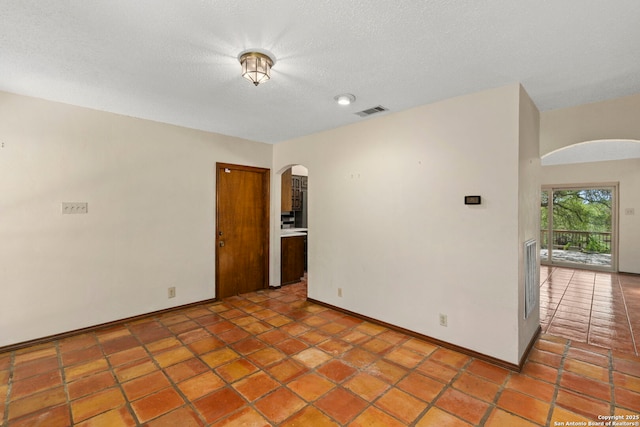 25615 Dull Knife Trl, San Antonio, TX 78255 - spare room with arched walkways, light tile patterned floors, and a textured ceiling