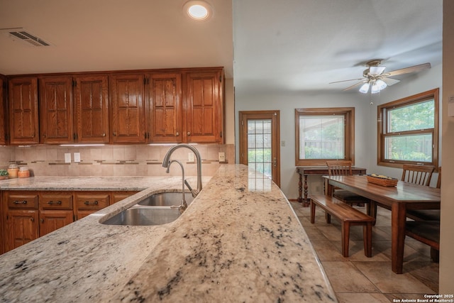 14519 Parksite Woods, San Antonio, TX 78249 - kitchen featuring brown cabinetry, decorative backsplash, and light stone countertops