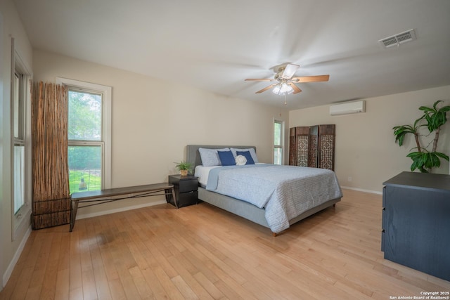 14519 Parksite Woods, San Antonio, TX 78249 - bedroom featuring a wall mounted AC, light wood-type flooring, and ceiling fan