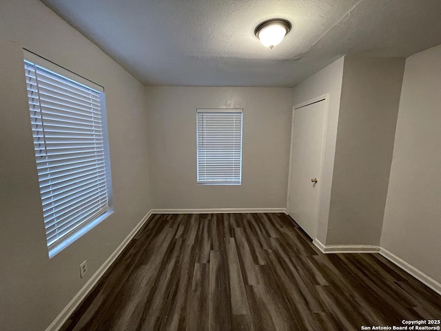 2025 Texas, San Antonio, TX 78228 - unfurnished bedroom with dark wood-style flooring, a textured ceiling, and multiple windows