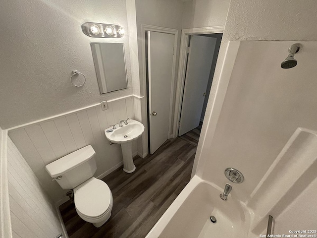 2025 Texas, San Antonio, TX 78228 - full bathroom with wood finished floors, wainscoting, a textured wall, tub / shower combination, and wooden walls