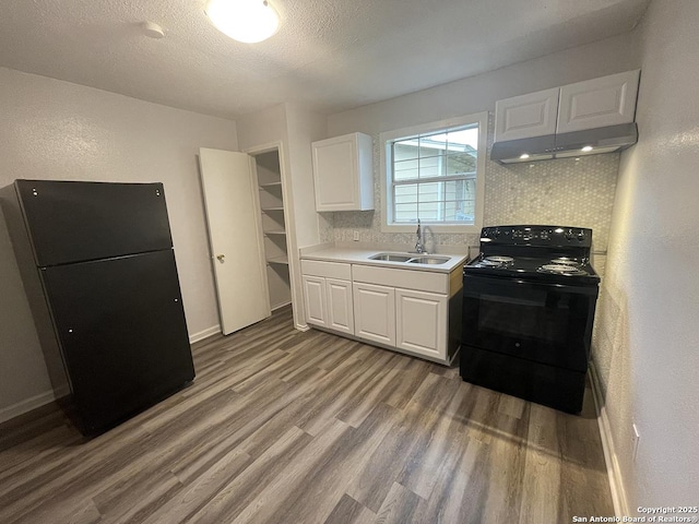 2025 Texas, San Antonio, TX 78228 - kitchen with black appliances, under cabinet range hood, wood finished floors, white cabinets, and light countertops