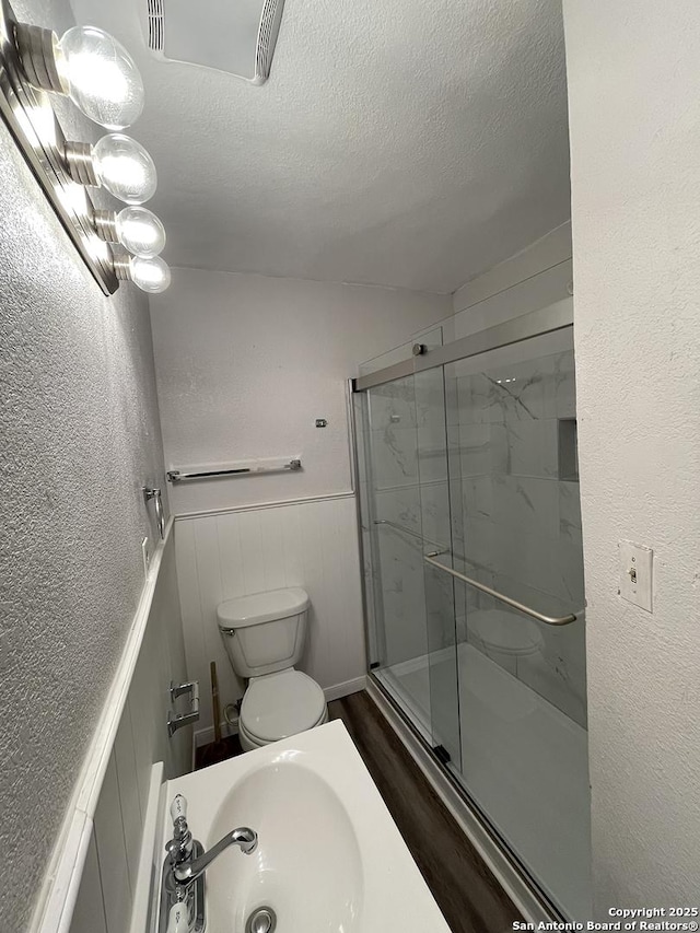 2025 Texas, San Antonio, TX 78228 - full bath featuring a textured ceiling, a shower stall, wainscoting, and wood finished floors