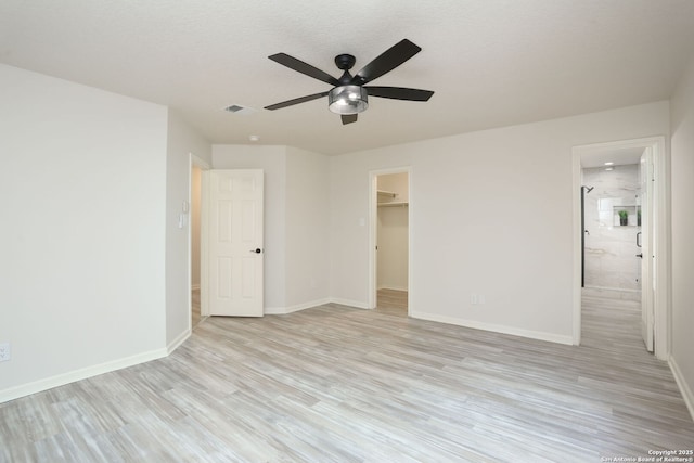16063 Walnut Crk, San Antonio, TX 78247 - unfurnished bedroom with light wood-type flooring, a spacious closet, a closet, ensuite bathroom, and a ceiling fan