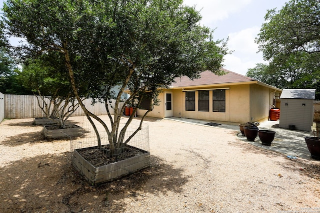 16063 Walnut Crk, San Antonio, TX 78247 - rear view of property featuring a shed, a vegetable garden, a fenced backyard, stucco siding, and a patio