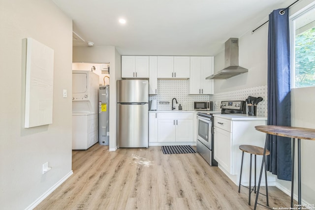 619 Olney Dr, San Antonio, TX 78209 - kitchen with wall chimney exhaust hood, stainless steel appliances, stacked washer / drying machine, electric water heater, and white cabinetry