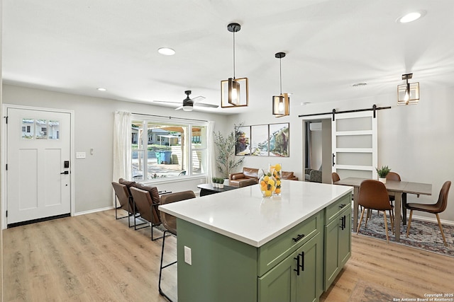 619 Olney Dr, San Antonio, TX 78209 - kitchen with green cabinets, a barn door, a ceiling fan, a center island, and light wood-style flooring