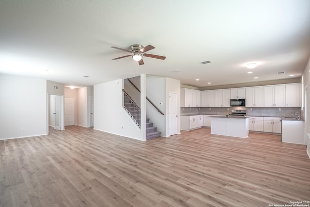 27422 Bighorn Sheep, Boerne, TX 78015 - kitchen featuring black microwave, open floor plan, stainless steel range oven, light wood-style flooring, and recessed lighting