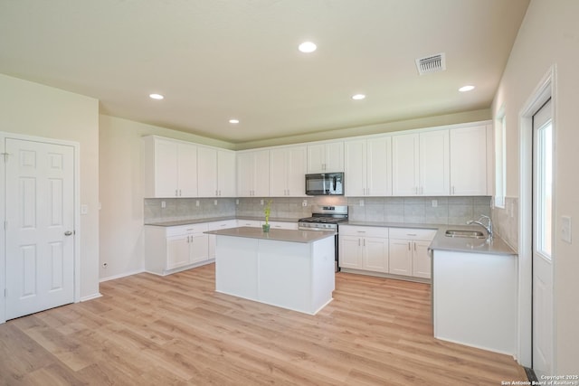27422 Bighorn Sheep, Boerne, TX 78015 - kitchen featuring black microwave, stainless steel gas range oven, a kitchen island, light wood-style floors, and recessed lighting