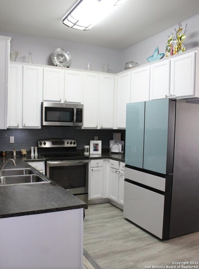 105 Yucca, Jourdanton, TX 78026 - kitchen with appliances with stainless steel finishes, dark countertops, white cabinetry, and tasteful backsplash