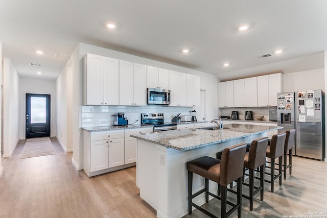 8030 Chanting, San Antonio, TX 78223 - kitchen featuring appliances with stainless steel finishes, light wood-style floors, a kitchen bar, decorative backsplash, and recessed lighting