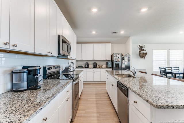 8030 Chanting, San Antonio, TX 78223 - kitchen with stainless steel appliances, a center island with sink, recessed lighting, white cabinetry, and light wood-style floors