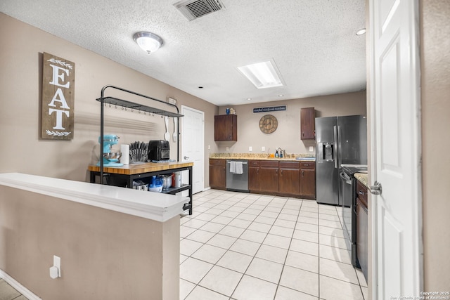 9830 Lauren Mist, San Antonio, TX 78251 - kitchen with stainless steel appliances, light countertops, light tile patterned floors, a textured ceiling, and dark brown cabinetry