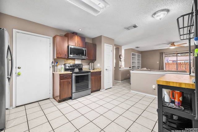 9830 Lauren Mist, San Antonio, TX 78251 - kitchen with appliances with stainless steel finishes, open floor plan, ceiling fan, a textured ceiling, and light tile patterned flooring