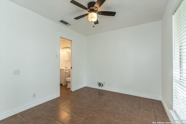 142 Meadow, Converse, TX 78109 - unfurnished bedroom with multiple windows, dark tile patterned floors, a textured ceiling, ensuite bath, and a ceiling fan