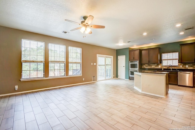 4763 Bending Grv, San Antonio, TX 78259 - kitchen with appliances with stainless steel finishes, open floor plan, healthy amount of natural light, ceiling fan, and a textured ceiling