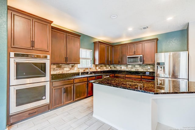 4763 Bending Grv, San Antonio, TX 78259 - kitchen with appliances with stainless steel finishes, backsplash, dark stone countertops, a kitchen island, and recessed lighting