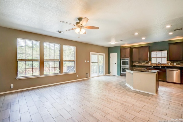 4763 Bending Grv, San Antonio, TX 78259 - kitchen with appliances with stainless steel finishes, open floor plan, a ceiling fan, dark countertops, and healthy amount of natural light