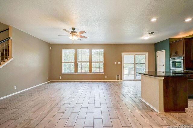 4763 Bending Grv, San Antonio, TX 78259 - kitchen with ceiling fan, dark countertops, open floor plan, light wood-type flooring, and a textured ceiling