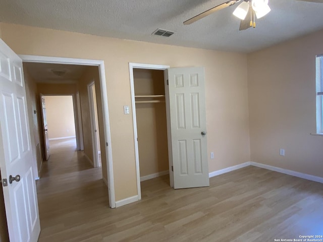 305 Osage, Refugio, TX 78377 - unfurnished bedroom with light wood-type flooring, a closet, ceiling fan, and a textured ceiling