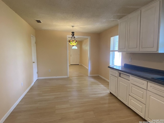 305 Osage, Refugio, TX 78377 - kitchen with light wood-style flooring, a textured ceiling, white cabinetry, dark countertops, and decorative light fixtures