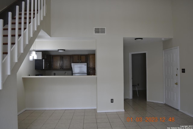 4107 Medical Dr Unit 8204, San Antonio, TX 78229 - kitchen with freestanding refrigerator, a high ceiling, dark brown cabinetry, stainless steel microwave, and light tile patterned floors