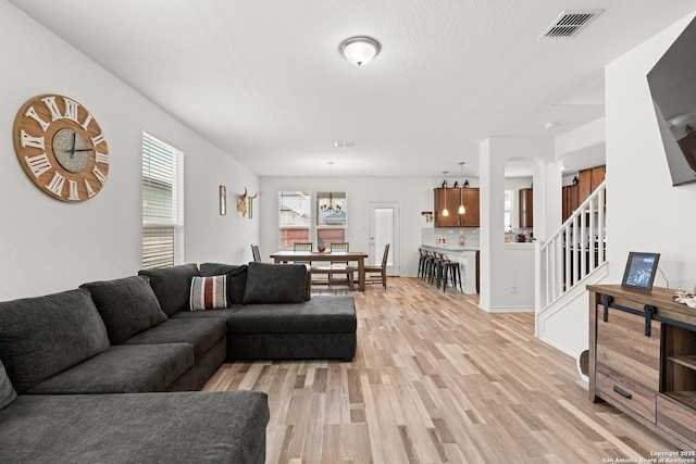 6583 Runaway, Converse, TX 78109 - living room featuring light wood-type flooring, stairway, arched walkways, and a chandelier