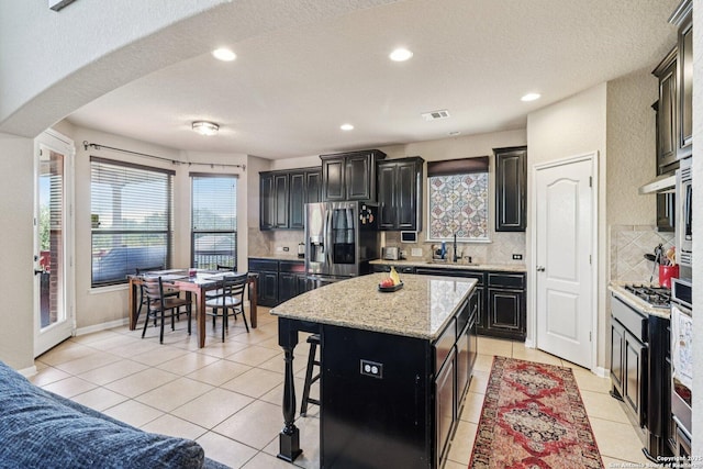 630 Oxalis, San Antonio, TX 78260 - kitchen with stainless steel appliances, dark cabinets, light tile patterned floors, decorative backsplash, and a kitchen island