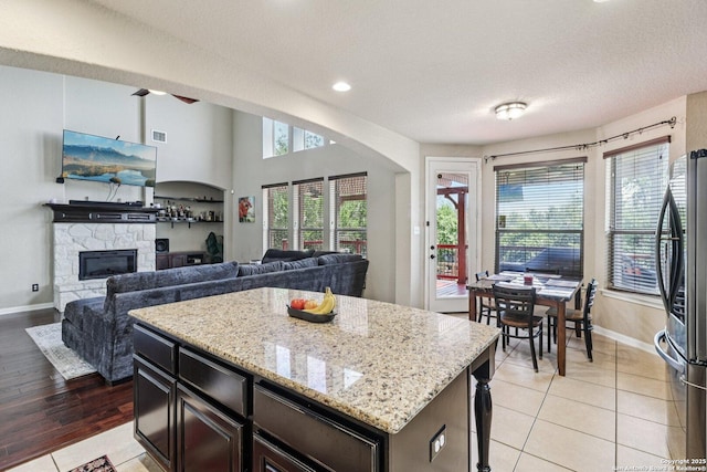 630 Oxalis, San Antonio, TX 78260 - kitchen featuring smart refrigerator, light stone countertops, a fireplace, a center island, and light tile patterned floors