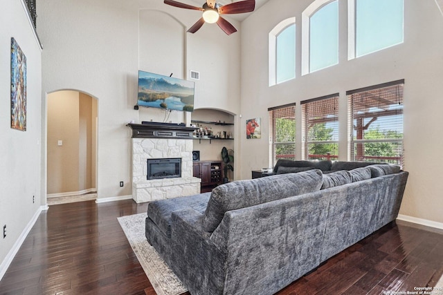 630 Oxalis, San Antonio, TX 78260 - living area with ceiling fan, arched walkways, dark wood-style floors, a high ceiling, and a stone fireplace